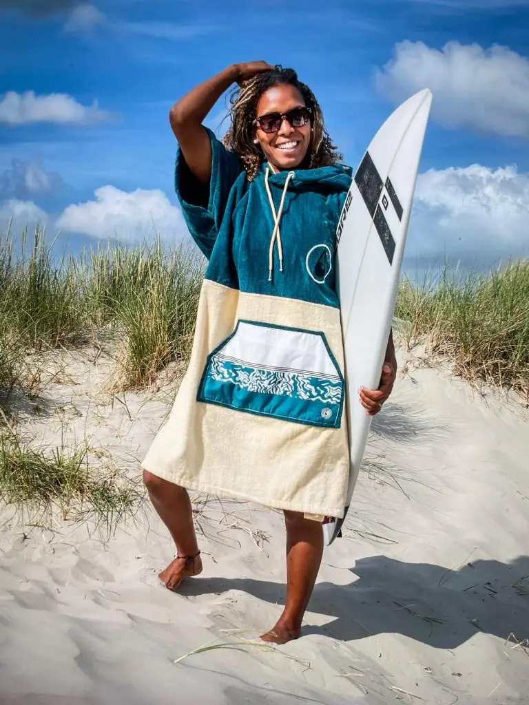 Femeie cu o placa de surf care poarta un poncho plaja dama din bumbac, culoare petrol si alb-crem